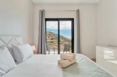 a bedroom with a large white bed with a window at Sonhos na Iha III by Holiday Rental Madeira in Campanário