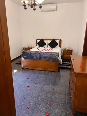 a bedroom with a bed with red flower petals on the floor at Retiro encantador em Machico - 5 min Praia e Centro A in Machico