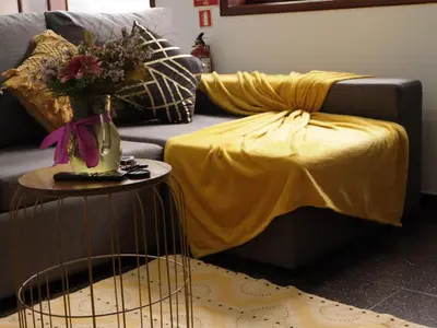 a living room with a couch with a yellow blanket at Retiro encantador em Machico - 5 min Praia e Centro A in Machico