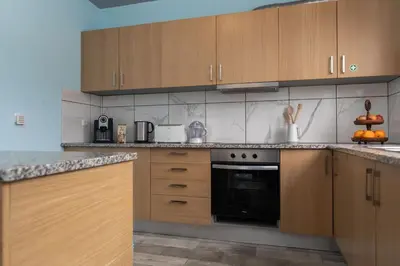 a kitchen with wooden cabinets and a black oven at Casa Vale Sereno by Rent-a-key in Cabo da Ribeira
