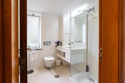 a white bathroom with a toilet and a glass shower at GuestReady - Relaxing escape with pool in Funchal