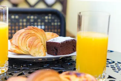 a plate of bread and orange juice next to two glasses of orange juice at GuestReady - Idyllic vacation with stunning views in Caniço