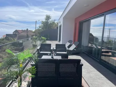 a balcony with chairs and a view of the ocean at Villa Bacana Oasis in Estreito da Calheta