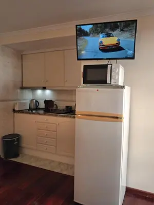 a kitchen with a refrigerator and a tv on the wall at Ribeira Brava Studios - M in Ribeira Brava
