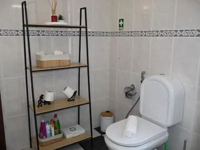 a bathroom with a toilet and shelves in it at Charming Retreat Machico - 5 min Praia & Centro B in Machico