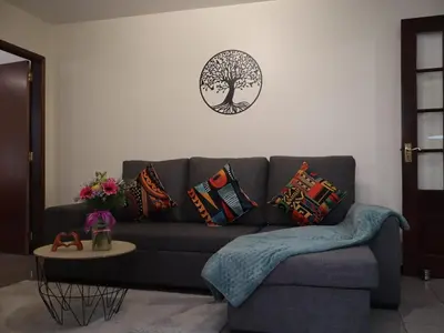 a living room with a couch with pillows and a clock at Charming Retreat Machico - 5 min Praia & Centro B in Machico