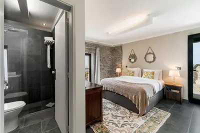 a bedroom with a king sized bed and a bathroom at Villa Clementina | Cliffs&Ocean | Heated Pool in Prazeres