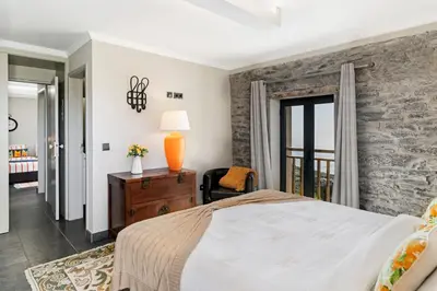 a bedroom with a bed and a stone wall at Villa Clementina | Cliffs&Ocean | Heated Pool in Prazeres