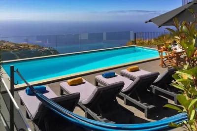 a pool with chairs and a hammock next to a swimming pool at Villa Clementina | Cliffs&Ocean | Heated Pool in Prazeres