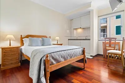 a bedroom with a large bed and a kitchen at Ribeira Brava Studios - H in Ribeira Brava