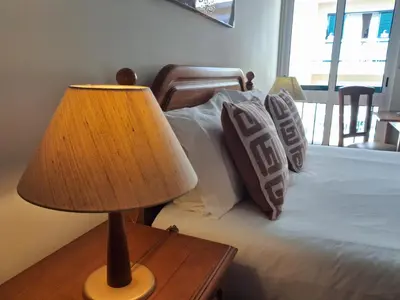 a lamp on a table next to a bed with pillows at Ribeira Brava Studios - L in Ribeira Brava