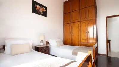 a bedroom with two beds and a wooden door at Ideia Cottage - Sea View in Ribeira Brava