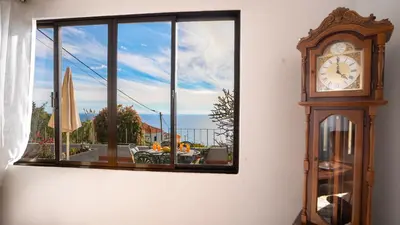a grandfather clock sitting in front of a window at Ideia Cottage - Sea View in Ribeira Brava