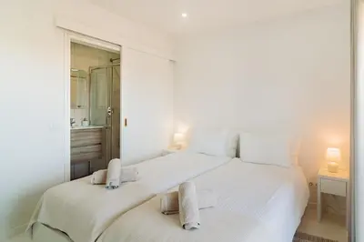 a white bedroom with a large white bed and a mirror at Family & Friends in Sagres