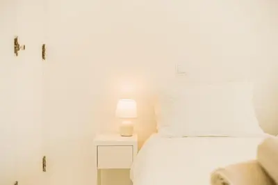 a bedroom with a white bed and a lamp on a nightstand at Family & Friends in Sagres