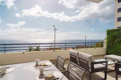 a balcony with tables and chairs and a view of the ocean at GuestReady - Relaxing moment in Caniço in Caniço