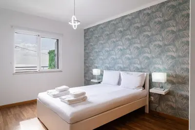 a bedroom with a bed with white sheets and a wall at GuestReady - Relaxing moment in Caniço in Caniço