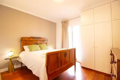 a bedroom with a bed with white sheets and a window at Funchal Terrace House in Funchal