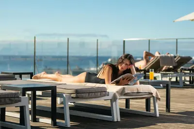 a woman in a bikini laying on a bed on a beach at Castanheiro Boutique Hotel in Funchal