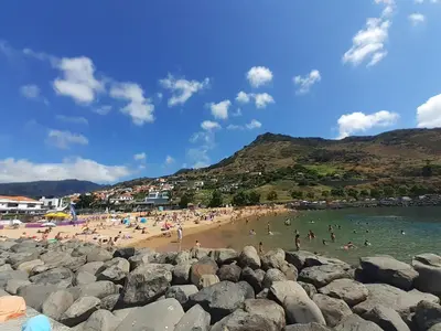 a group of people swimming in the water at a beach at GuestRedy - A Modern Stay in Machico in Machico