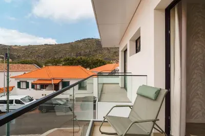 a chair on a balcony with a view of a street at GuestRedy - A Modern Stay in Machico in Machico