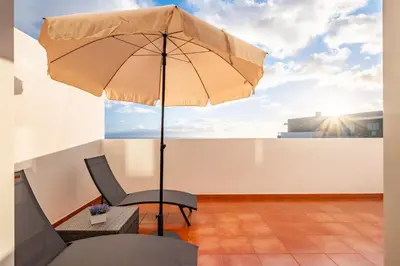 a patio with a chair and an umbrella at Modern Suburban Haven in Caniço