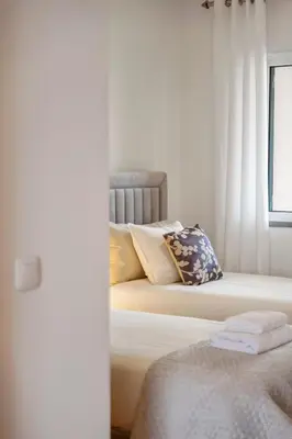 a bedroom with two beds with pillows and a window at Modern Suburban Haven in Caniço