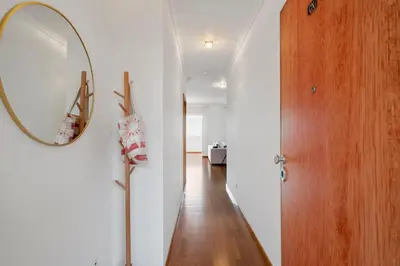 a hallway with a mirror and a wooden door at Modern Suburban Haven in Caniço
