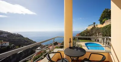 a balcony with a table and chairs and the ocean at Calheta, Sun, Sea & Pool in Calheta
