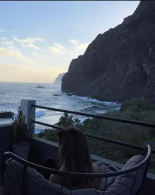 a woman sitting in a hammock looking at the ocean at Dhamma Guest House in Ponta Delgada