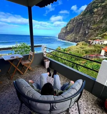 two people laying in a chair looking at the ocean at Dhamma Guest House in Ponta Delgada