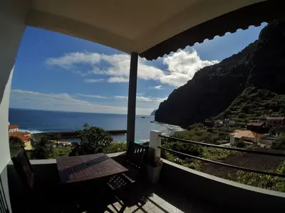 a balcony with a table and a view of the ocean at Dhamma Guest House in Ponta Delgada