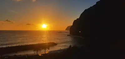 a sunset over the ocean with the sun setting at Dhamma Guest House in Ponta Delgada