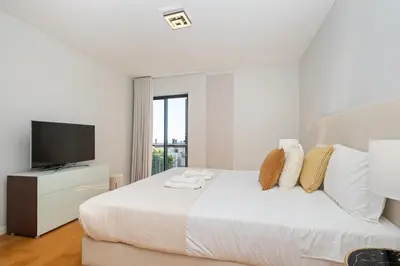 a white bedroom with a bed and a television at Fórum Glam 5B by Homie in Funchal