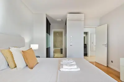 a white bedroom with a large white bed with towels on it at Fórum Glam 5B by Homie in Funchal