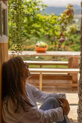 a woman sitting in a chair looking out a window at The Yellow Cottage Nature House São Vicente Madeira Island in São Vicente