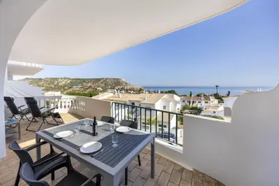 a dining table on a balcony with a view of the ocean at CoolHouses Algarve Luz, Ramalhete in Luz