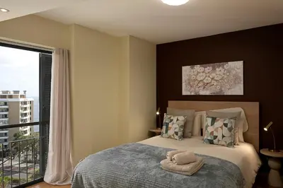 a bedroom with a large bed with a window at JOY Forum I in Funchal