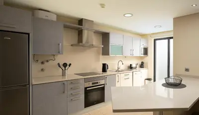 a kitchen with white cabinets and a black refrigerator at JOY Forum I in Funchal