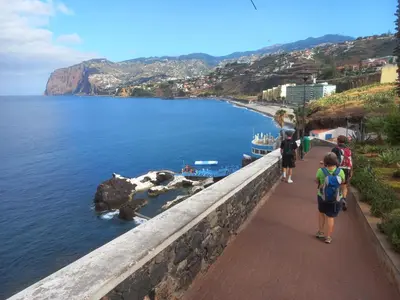 a group of people walking on a sidewalk near the water at Monumental Sur Mer in Funchal