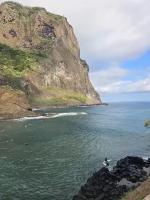 a group of people swimming in the water near a mountain at Casa da Cruz in Porto da Cruz