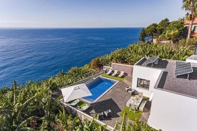 an aerial view of a house with a swimming pool and the ocean at Villa Graycis House by Villa Plus in Arco da Calheta