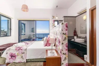 a bedroom with a bed and a bathroom with a sink at Villa Graycis House by Villa Plus in Arco da Calheta