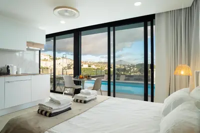 a bedroom with a large white bed and a table with chairs at Calma Retreat - Pool & Lodge in Câmara de Lobos