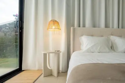 a bedroom with a bed and a lamp next to a window at Calma Retreat - Pool & Lodge in Câmara de Lobos