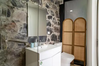 a bathroom with a white sink and a stone wall at Calma Retreat - Pool & Lodge in Câmara de Lobos