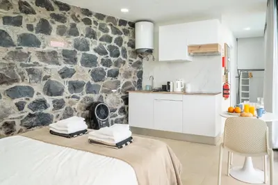 a kitchen with a table and a stone wall at Calma Retreat - Pool & Lodge in Câmara de Lobos