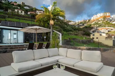a living room with a white couch and an umbrella at Calma Retreat - Pool & Lodge in Câmara de Lobos