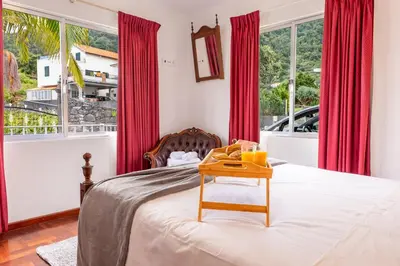 a bedroom with red curtains and a bed with a table at Solar do Pico Apartment in Ponta Delgada
