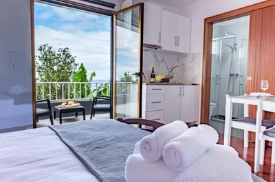 a room with a bed and a kitchen with a balcony at Solar do Pico Studio in Ponta Delgada